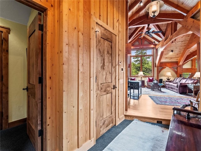 interior space featuring carpet flooring, lofted ceiling with beams, ceiling fan, and wood ceiling