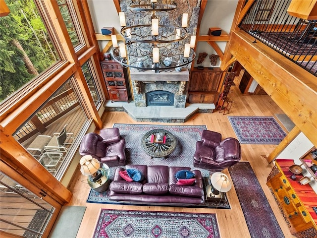 living room featuring a stone fireplace, a high ceiling, and hardwood / wood-style flooring