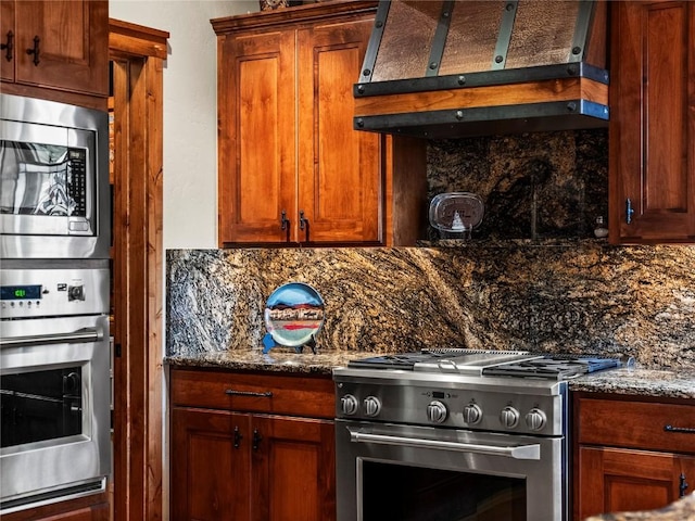 kitchen featuring appliances with stainless steel finishes, backsplash, extractor fan, and dark stone countertops