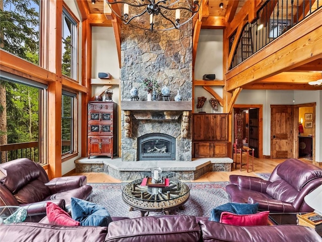 living room featuring a stone fireplace, a towering ceiling, wood-type flooring, and an inviting chandelier