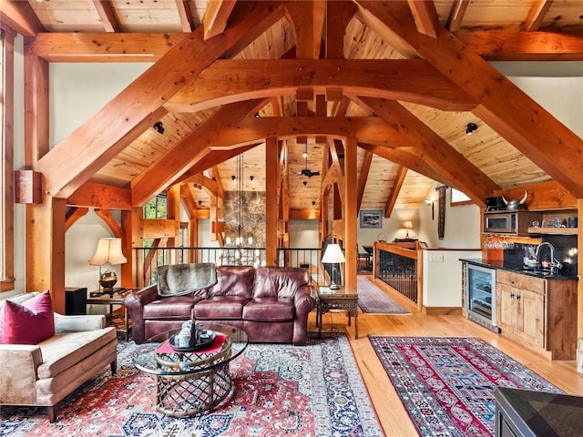 living room featuring sink, wooden ceiling, beverage cooler, vaulted ceiling with beams, and light wood-type flooring