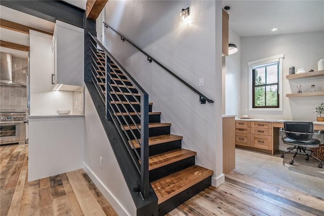 stairs featuring vaulted ceiling with beams, hardwood / wood-style floors, and built in desk