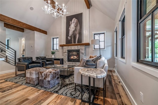 living room featuring high vaulted ceiling, an inviting chandelier, a stone fireplace, beam ceiling, and wood-type flooring