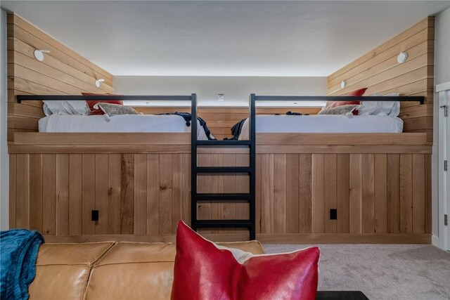 carpeted bedroom featuring wooden walls