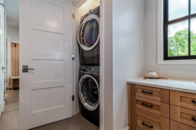 laundry area with light tile patterned floors and stacked washer and clothes dryer