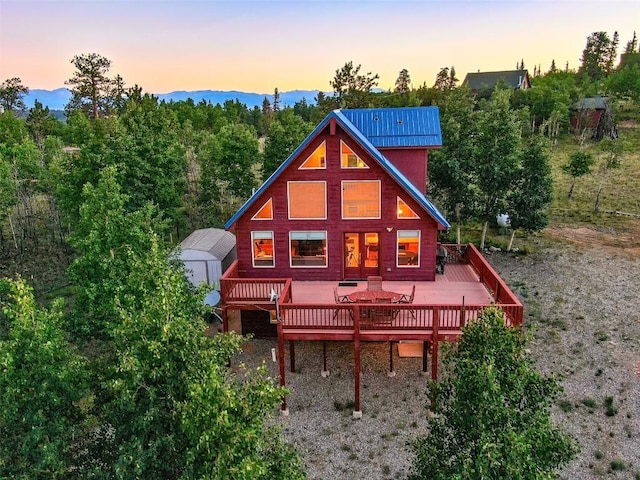 back house at dusk with a deck and a storage unit