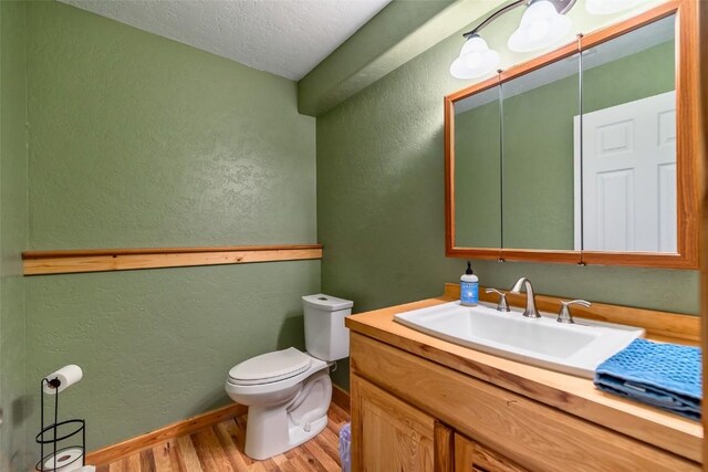 bathroom featuring hardwood / wood-style flooring, vanity, toilet, and a textured ceiling