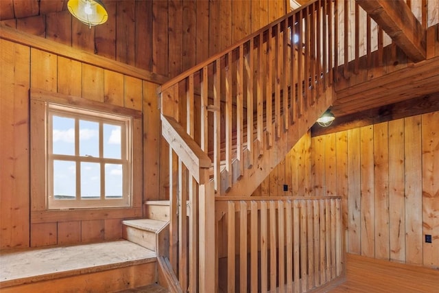 staircase with hardwood / wood-style floors and wood walls