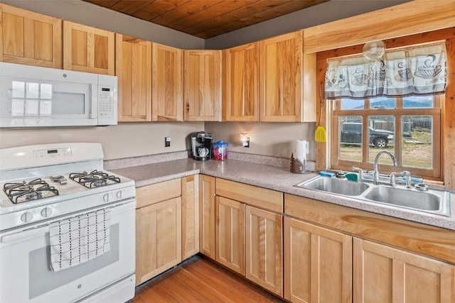 kitchen with sink, light hardwood / wood-style floors, white appliances, and light brown cabinets