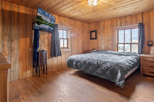 bedroom with hardwood / wood-style flooring, wood ceiling, and wooden walls