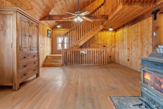 unfurnished living room with ceiling fan, wooden ceiling, vaulted ceiling with beams, light hardwood / wood-style floors, and wooden walls