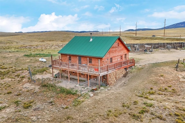 back of property with a deck with mountain view and a rural view