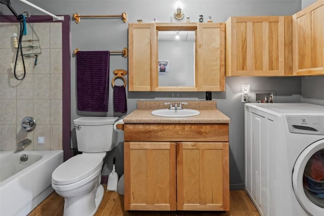 interior space featuring vanity, hardwood / wood-style flooring, tiled shower / bath combo, toilet, and washer / dryer