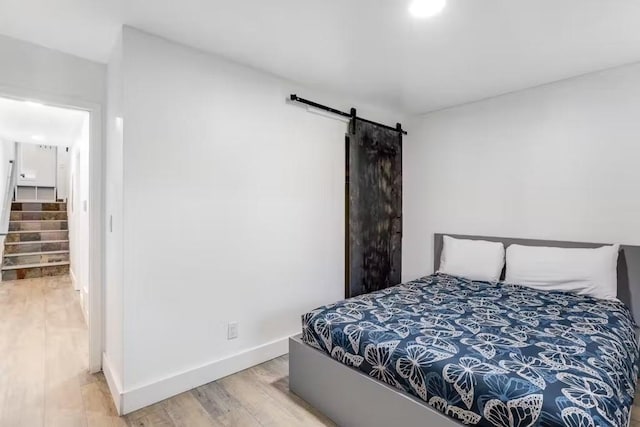 bedroom featuring a barn door and hardwood / wood-style flooring