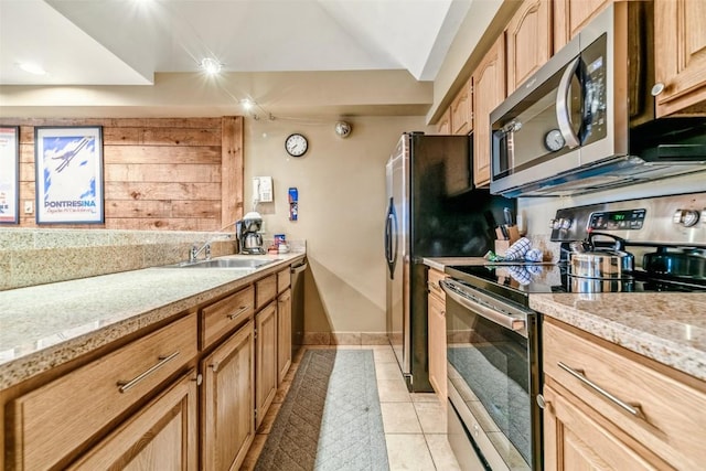 kitchen with light stone counters, light tile patterned floors, appliances with stainless steel finishes, and a sink