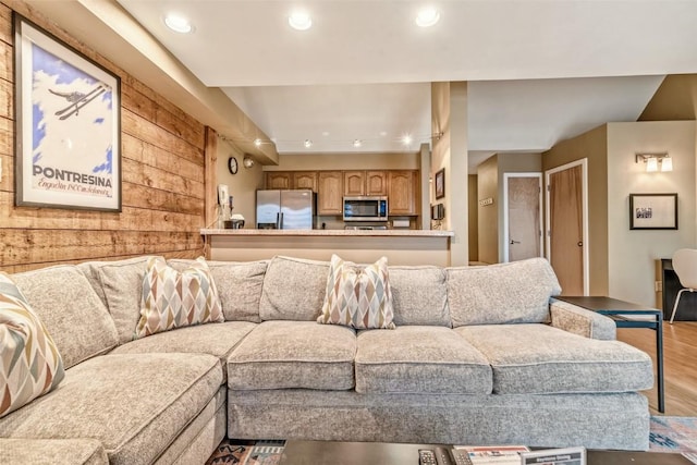 living room with recessed lighting, wood finished floors, and wood walls