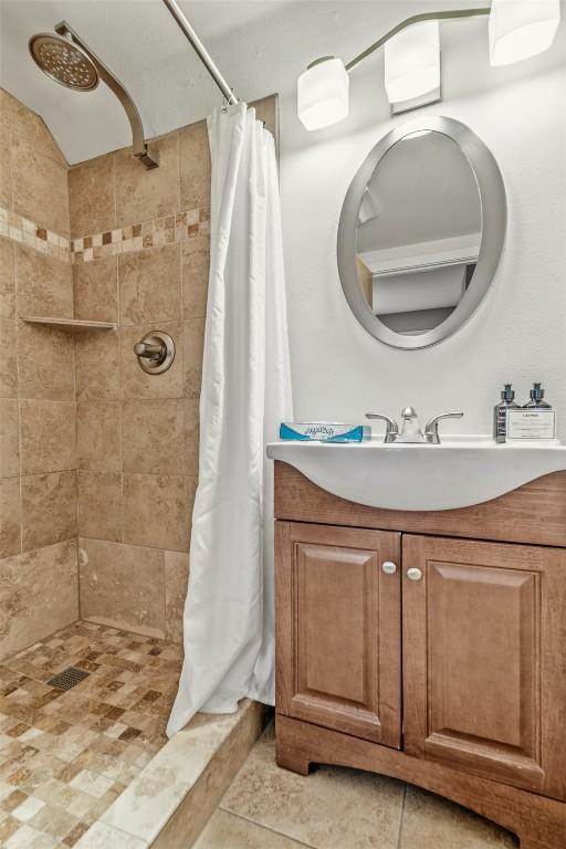 bathroom featuring tile patterned floors, vanity, and a tile shower