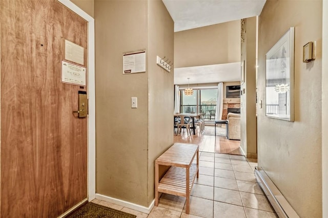 hallway featuring light tile patterned floors, baseboards, and baseboard heating