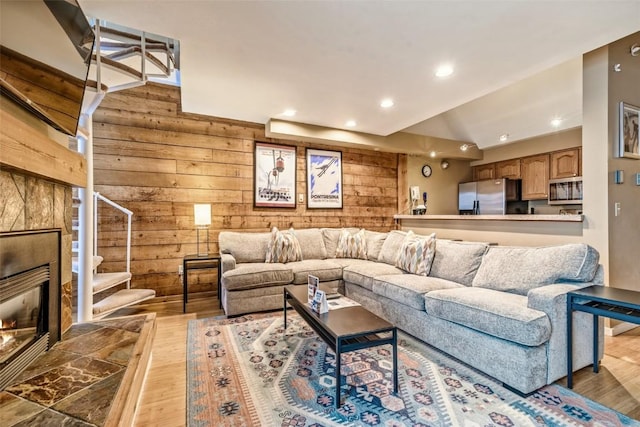 living area with wood walls, stairs, vaulted ceiling, recessed lighting, and wood finished floors