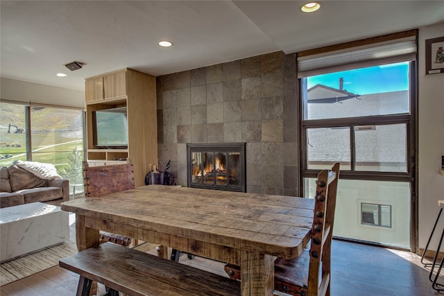 dining room with a fireplace, hardwood / wood-style floors, plenty of natural light, and tile walls