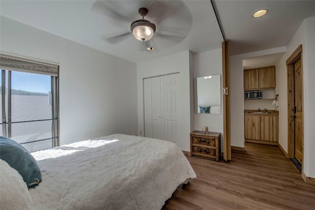 bedroom with ceiling fan, sink, a closet, a water view, and hardwood / wood-style flooring