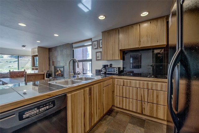 kitchen with tile countertops, a tile fireplace, black appliances, sink, and decorative backsplash