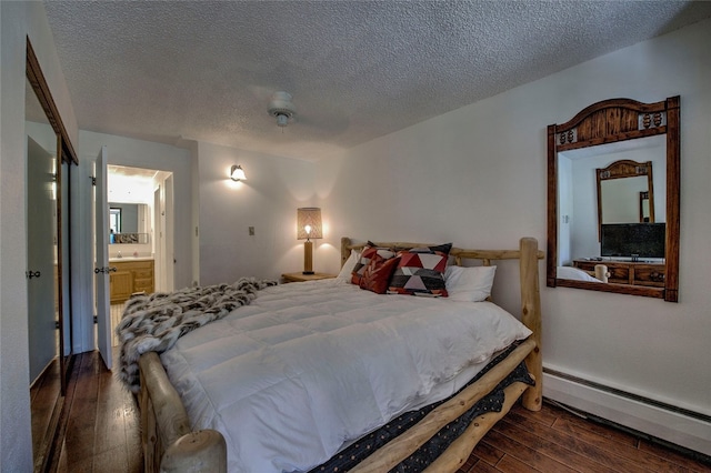 bedroom featuring connected bathroom, ceiling fan, dark wood-type flooring, a baseboard heating unit, and a textured ceiling