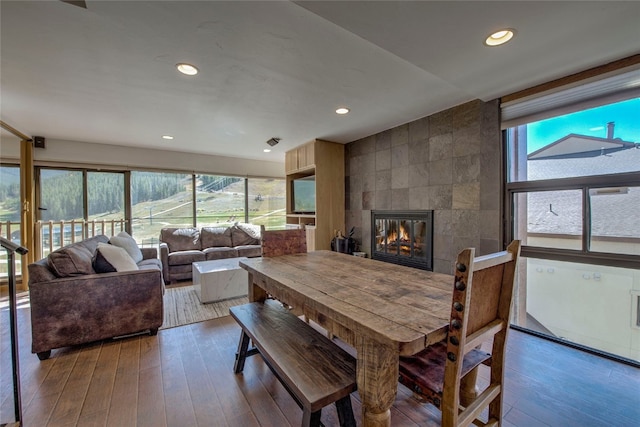 dining room featuring a fireplace, hardwood / wood-style floors, and tile walls