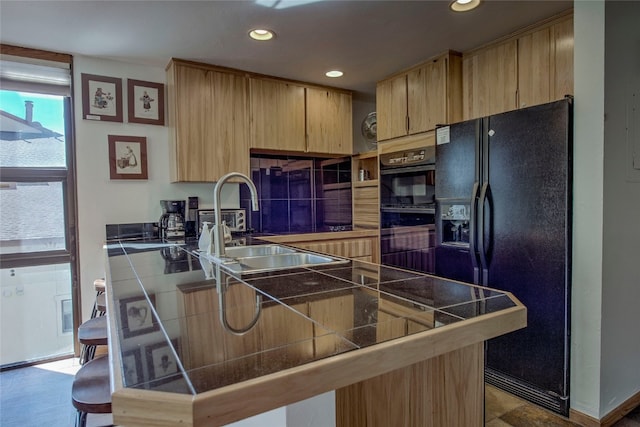 kitchen with light brown cabinets, black appliances, a kitchen breakfast bar, tile counters, and kitchen peninsula