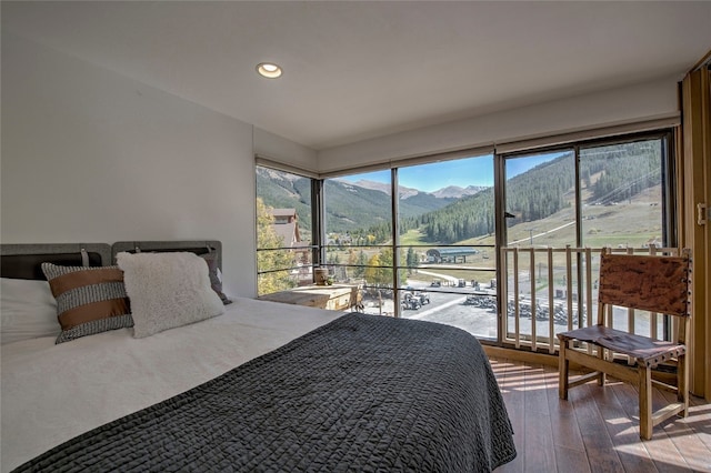 bedroom with hardwood / wood-style flooring, a mountain view, and multiple windows