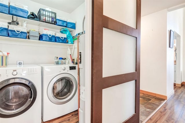 washroom with baseboards, wood finished floors, washing machine and dryer, and laundry area