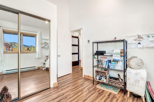 interior space featuring a baseboard heating unit, baseboards, and wood finished floors