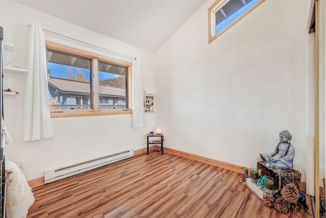 unfurnished room featuring vaulted ceiling, wood finished floors, baseboards, and baseboard heating