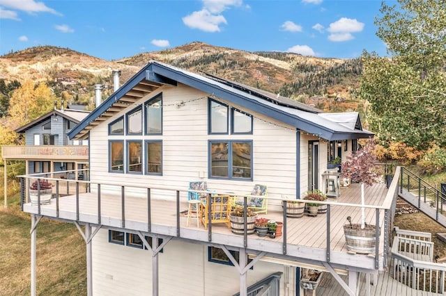 back of property with solar panels and a deck with mountain view