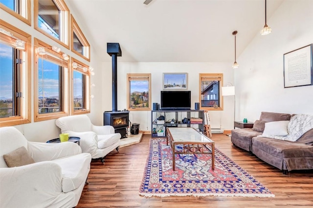 living room featuring baseboard heating, high vaulted ceiling, a wood stove, and wood finished floors