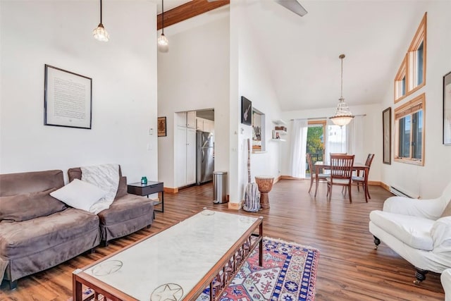 living room with a baseboard heating unit, wood finished floors, baseboards, and high vaulted ceiling