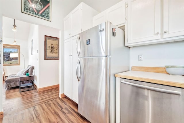 kitchen with baseboards, light wood-style flooring, stainless steel appliances, light countertops, and white cabinets