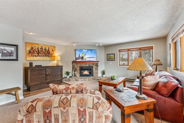 living room with light colored carpet, a stone fireplace, track lighting, and a textured ceiling