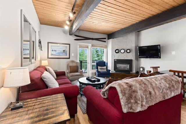 living room with beamed ceiling, a large fireplace, light hardwood / wood-style flooring, and wood ceiling