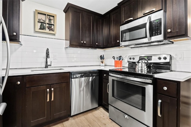 kitchen with light hardwood / wood-style floors, sink, appliances with stainless steel finishes, and tasteful backsplash