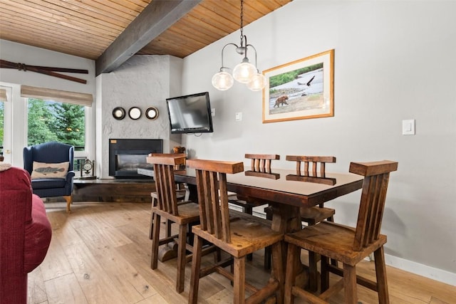 dining room with a fireplace, vaulted ceiling with beams, light hardwood / wood-style flooring, and wooden ceiling