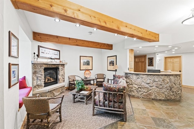 living room featuring beam ceiling and a stone fireplace