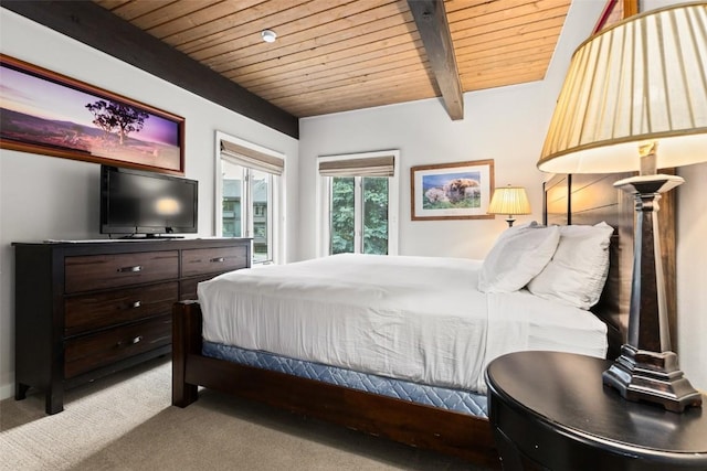 bedroom with beamed ceiling, light colored carpet, and wooden ceiling