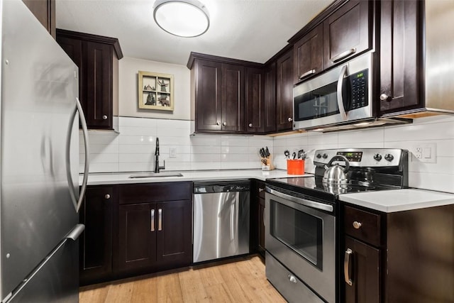 kitchen with decorative backsplash, dark brown cabinetry, stainless steel appliances, sink, and light hardwood / wood-style floors