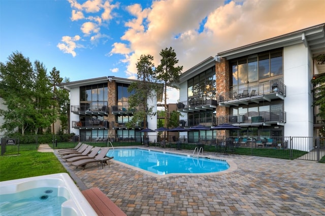 pool at dusk featuring a patio area and a jacuzzi