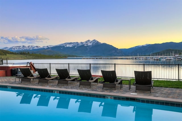 pool at dusk with a water and mountain view