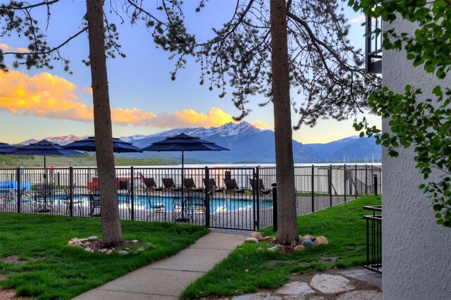 pool at dusk with a mountain view and a yard