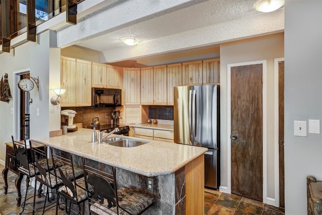 kitchen with kitchen peninsula, stainless steel fridge, light brown cabinetry, a breakfast bar, and sink