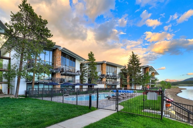 pool at dusk with a yard and a water view