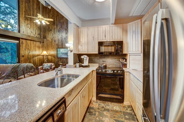 kitchen with light stone countertops, sink, ceiling fan, wood walls, and black appliances